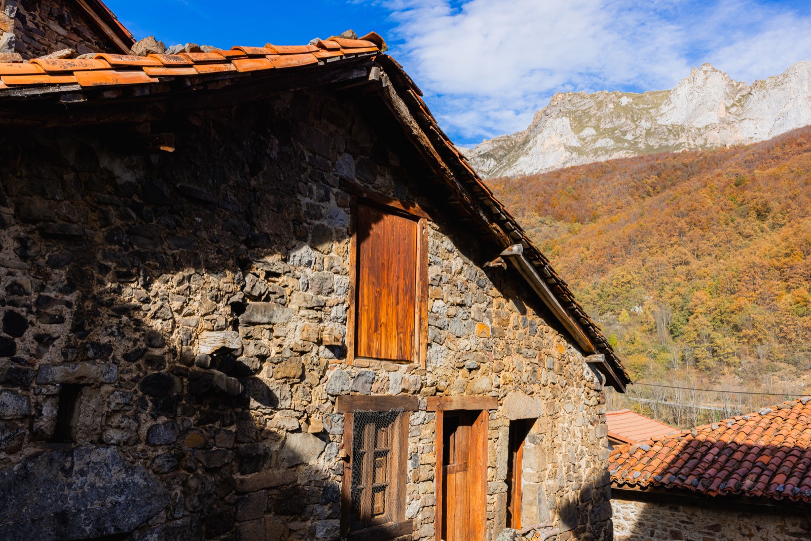 Casa de piedra y las montañas en otoño
